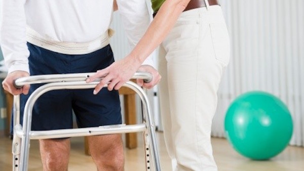 Physical therapist helping man walk